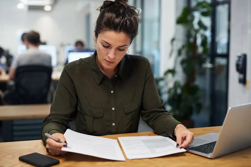 Trust and safety lead comparing printed vendor proposals for a dating app